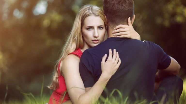 mulher abraçada ao marido olha para trás, em direção à câmera