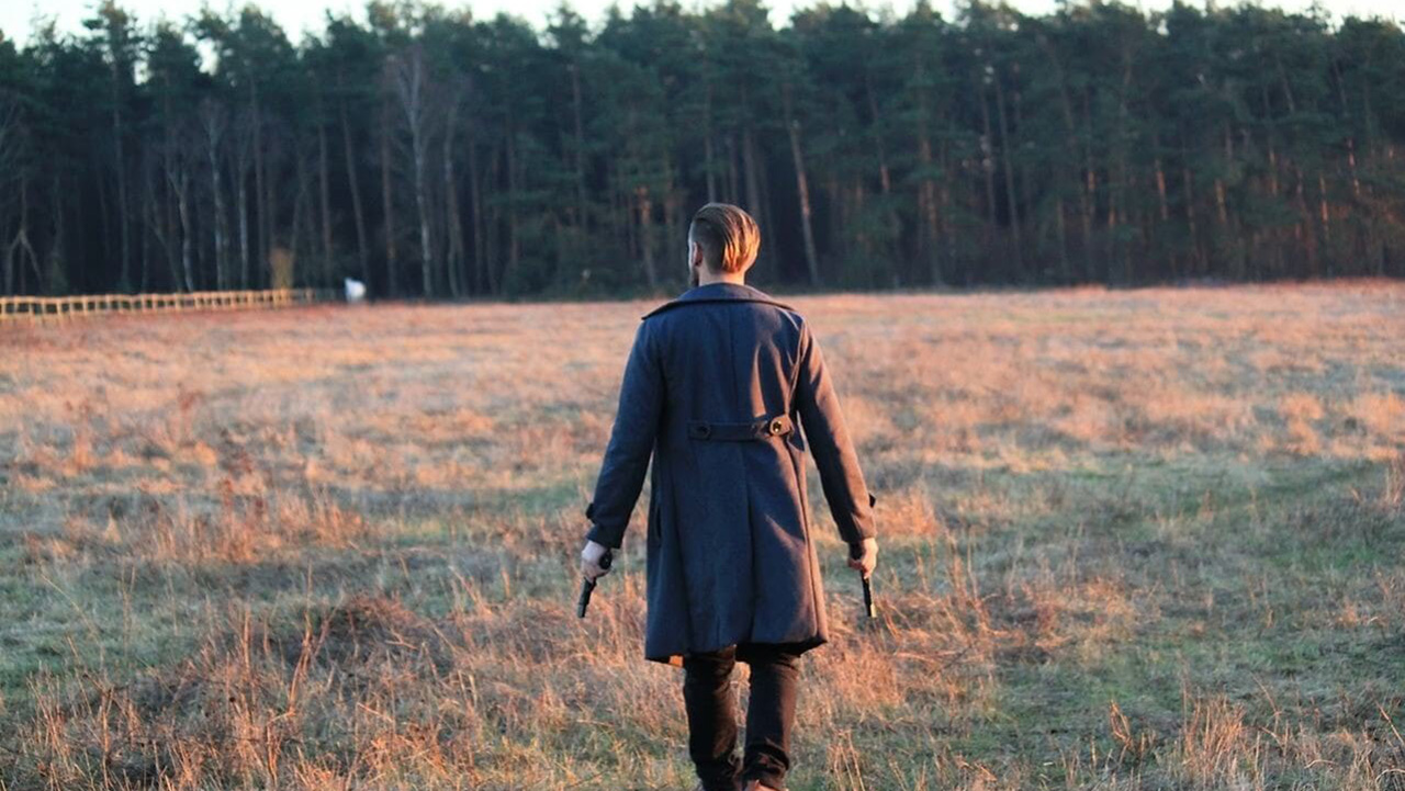 homem segurando duas pistolas em bosque