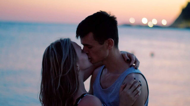 Casal se beijando durante pôr do sol na praia