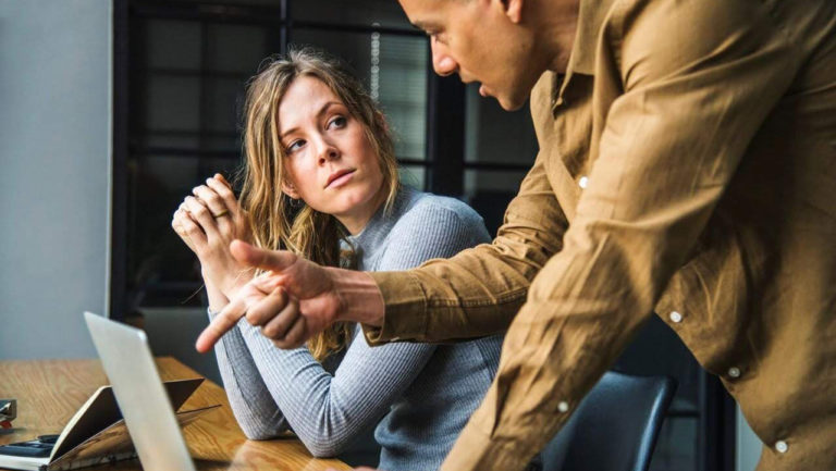 homem indicando tela de computador à mulher
