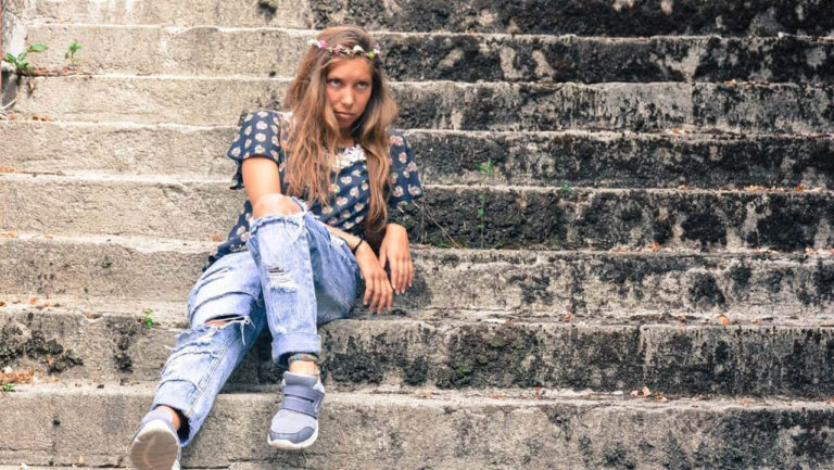 Mulher de olhar irritado sentada em degraus de escadaria
