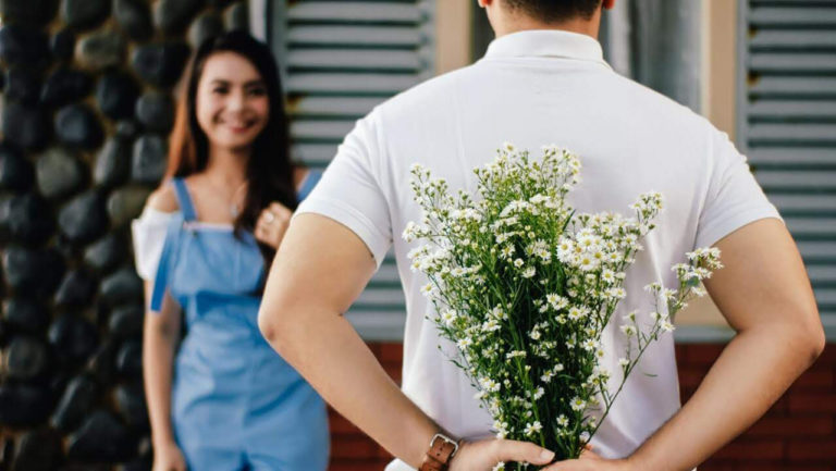 homem prestes a entregar buquê de flores a mulher