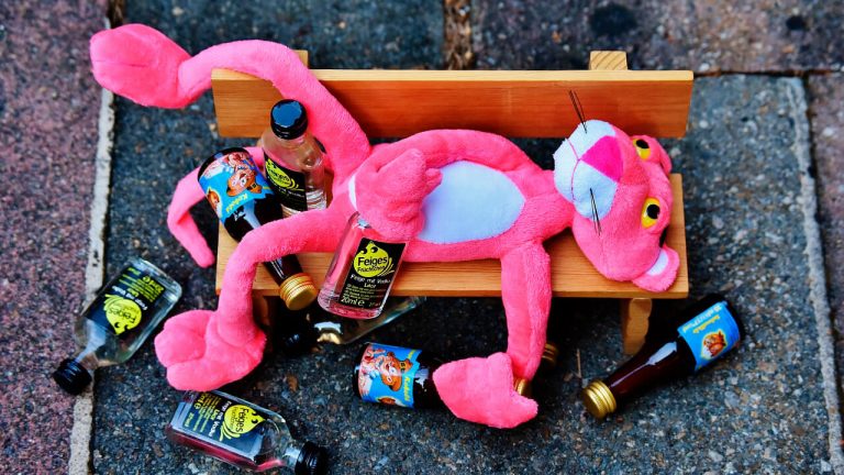 Pantera cor de rosa rodeada de garrafas de bebida alcoólica